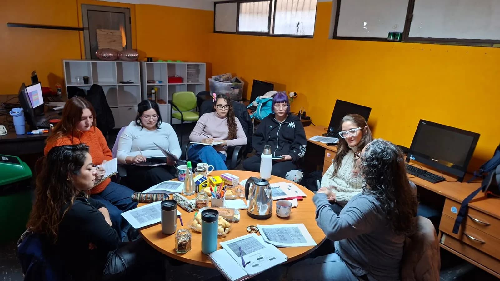 Docentes trabajan con materiales alrededor de una mesa